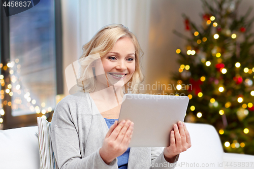 Image of happy woman with tablet pc at home on christmas