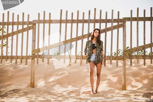 Image of Beautiful young woman posing near a wood fence