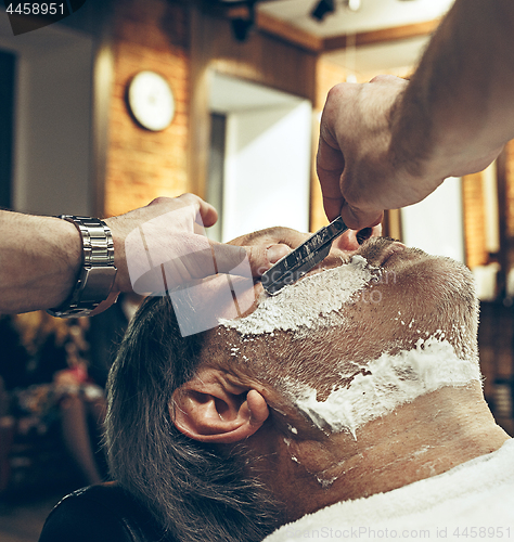 Image of Close-up side top view handsome senior bearded caucasian man getting beard grooming in modern barbershop.