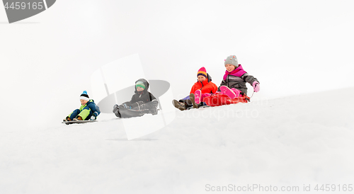 Image of kids sliding on sleds down snow hill in winter