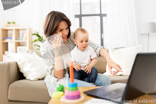 Image of working mother with baby calling on smartphone