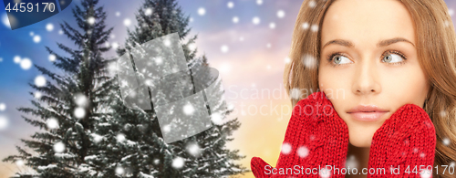 Image of close up of woman in mittens over christmas tree