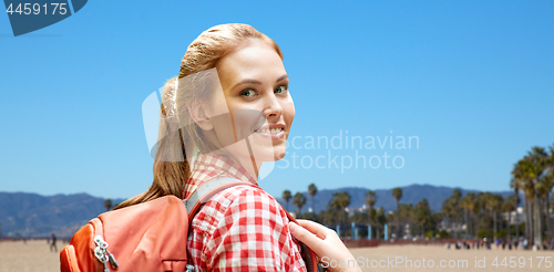 Image of smiling woman with backpack over venice beach