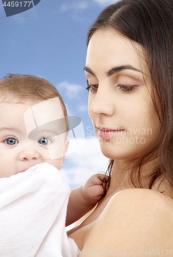 Image of mother with baby in bath towel over sky background