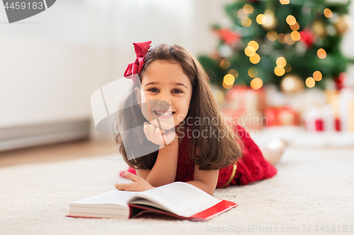 Image of happy girl reading book at home on christmas