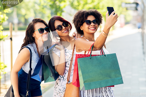 Image of women with shopping bags taking selfie in city