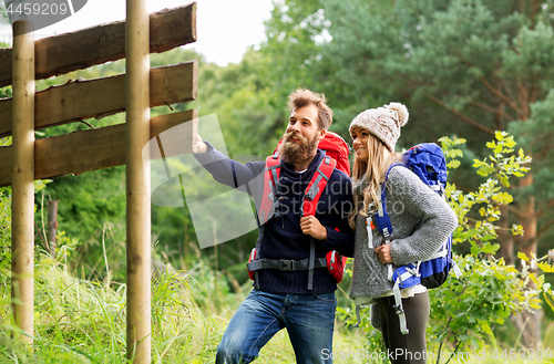 Image of couple of travelers with backpacks at signpost