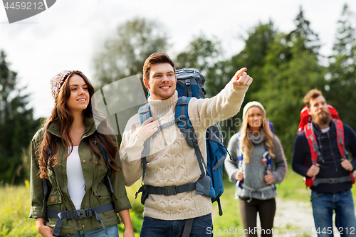 Image of happy friends or travelers with backpacks hiking
