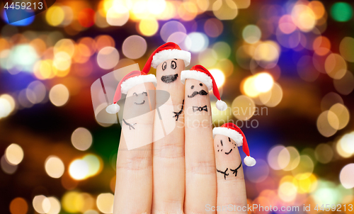 Image of close up of four fingers in santa hats over lights