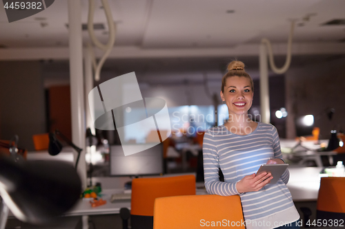 Image of woman working on digital tablet in night office