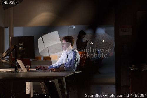 Image of man working on computer in dark office