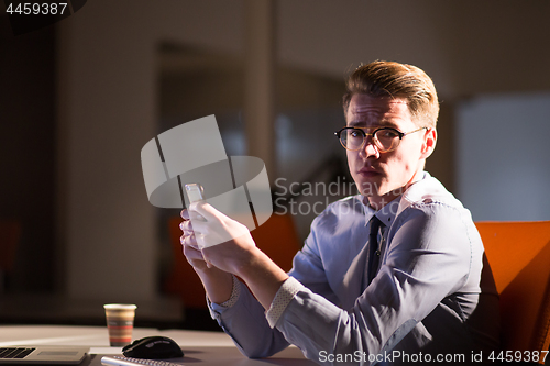 Image of man using mobile phone in dark office