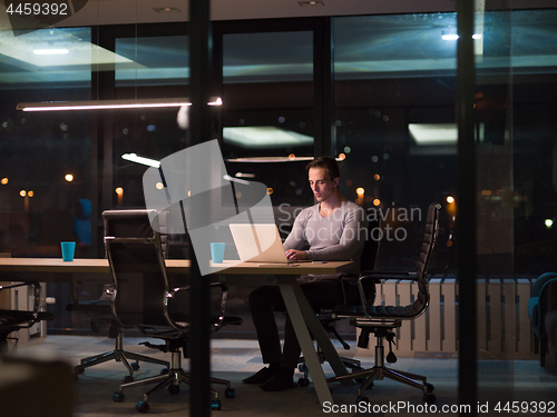 Image of man working on laptop in dark office