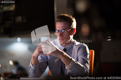 Image of man using mobile phone in dark office