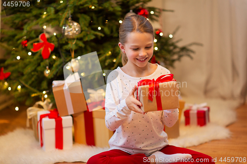 Image of smiling girl with christmas gift at home