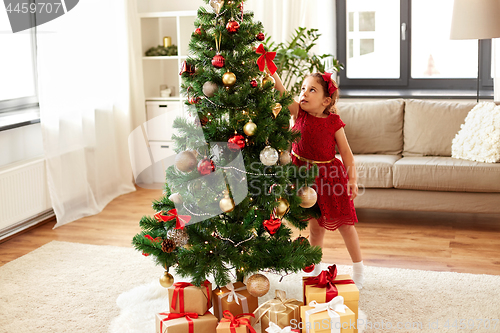 Image of little girl decorating christmas tree at home