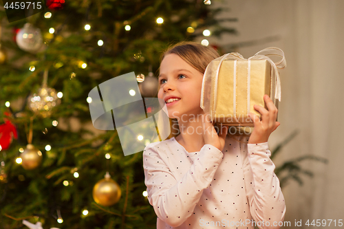 Image of smiling girl with christmas gift at home