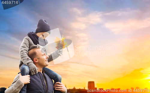 Image of father carrying son with autumn leaves in city