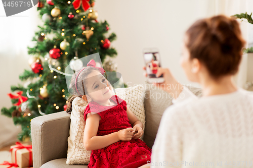Image of mother picturing daughter by phone on christmas