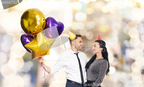 Image of happy couple with party caps and balloons