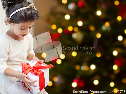 Image of happy little girl with christmas gift at home