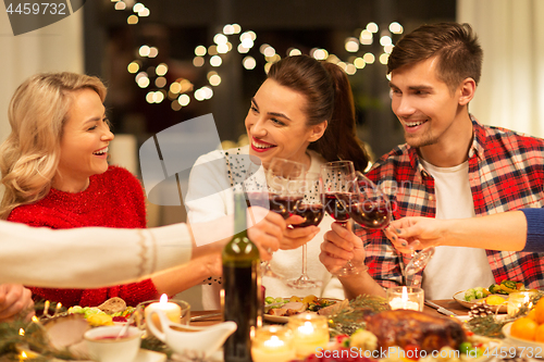 Image of happy friends drinking red wine at christmas party