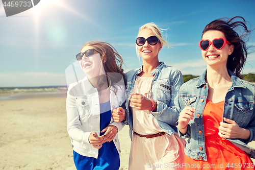 Image of group of smiling women in sunglasses on beach