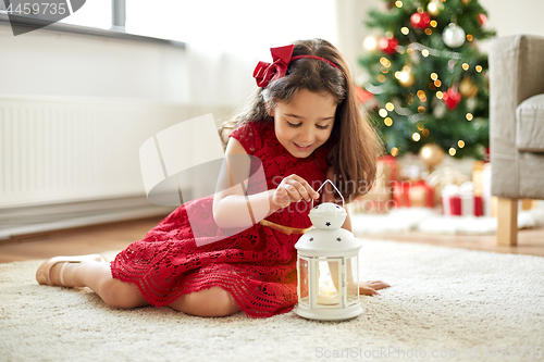 Image of little girl with lantern at home on christmas