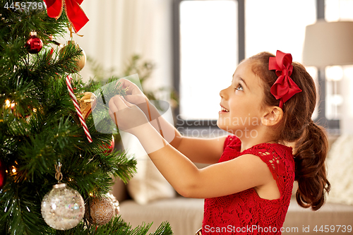 Image of little girl decorating christmas tree at home