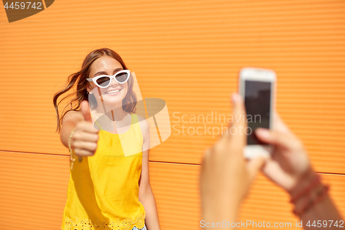 Image of teenage girl photographing friend by smartphone