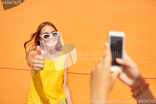 Image of teenage girl photographing friend by smartphone