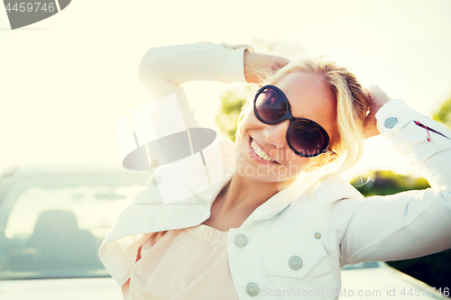 Image of happy teenage girl or young woman near car