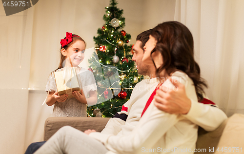 Image of happy family with christmas present at home