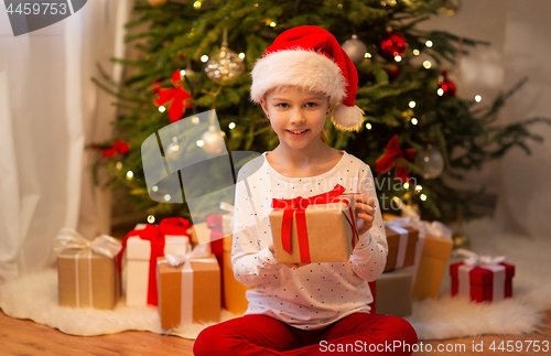 Image of smiling girl in santa hat with christmas gift