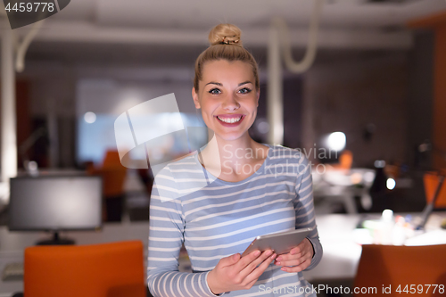 Image of woman working on digital tablet in night office