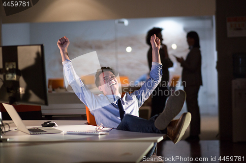 Image of businessman sitting with legs on desk at office