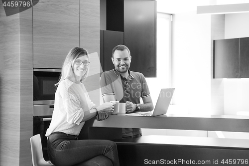 Image of couple drinking coffee and using laptop at home