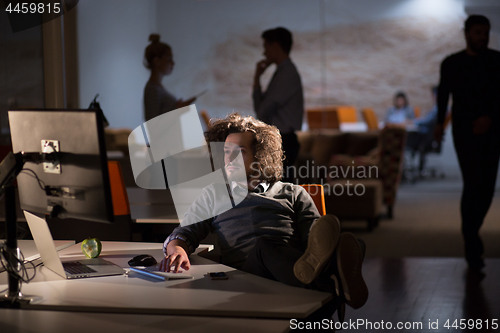 Image of businessman sitting with legs on desk at office