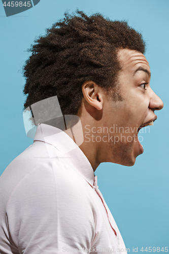 Image of The young emotional angry man screaming on blue studio background