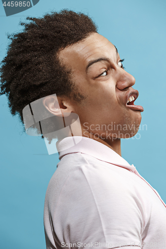 Image of Beautiful male half-length portrait isolated on blue studio backgroud. The young emotional surprised man