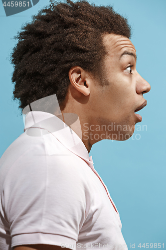 Image of The young attractive man looking suprised isolated on blue