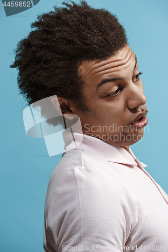 Image of Beautiful male half-length portrait isolated on blue studio backgroud. The young emotional surprised man