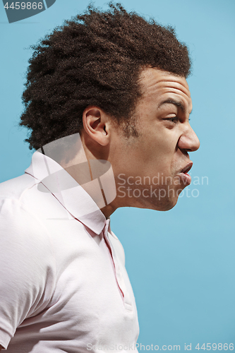 Image of The young emotional angry man screaming on blue studio background