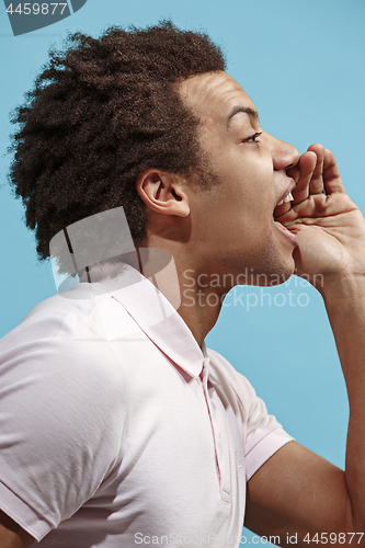 Image of Isolated on blue young casual man shouting at studio