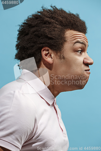 Image of The young emotional angry man screaming on blue studio background