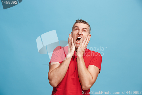 Image of The young attractive man looking suprised isolated on blue