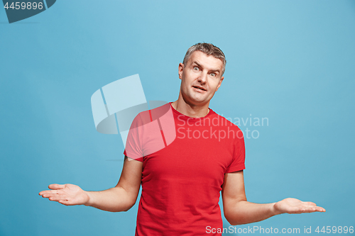 Image of The happy business man standing and smiling against blue background.