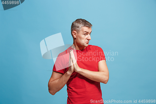 Image of The happy business man standing and smiling against blue background.