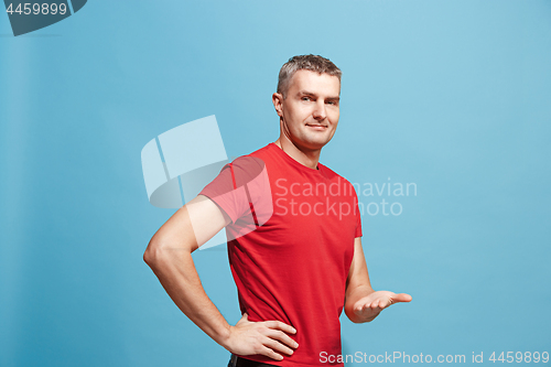 Image of The happy business man standing and smiling against blue background.