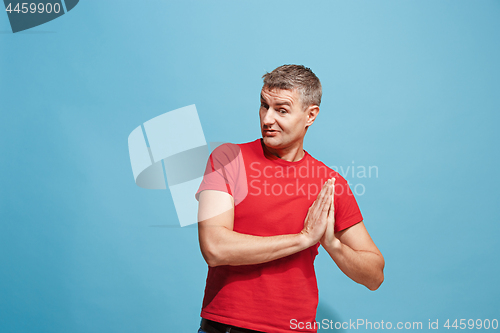 Image of The happy business man standing and smiling against blue background.
